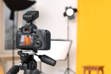 Modern fotoğraf stüdyosunda kamera, bar taburesi ve profesyonel ışıklandırma ekipmanı olan tripodlar ekrana odaklansın. Metin için boşluk