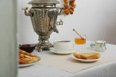 Vintage samovar, cup of hot drink and snacks served on table indoors. Traditional Russian tea ceremony