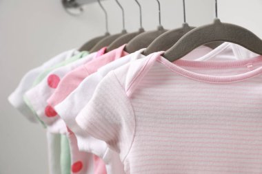 Beyaz arka planda bebek kıyafetleri olan askılar, yakın plan.