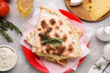 Peynirli lezzetli pizza dilimleri ve açık gri masadaki farklı ürünler.