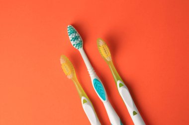 Turuncu arka planda yeni diş fırçaları, düz yatış