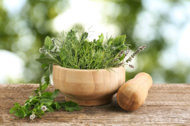 Havan topu ve farklı otlar dışarıda, ahşap masada.