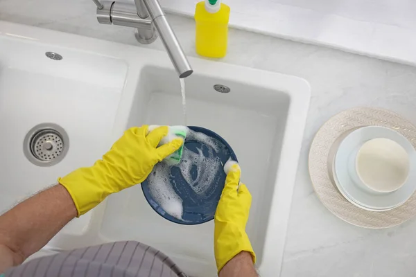 戴防护手套的男人在室内洗碗盘上方 — 图库照片