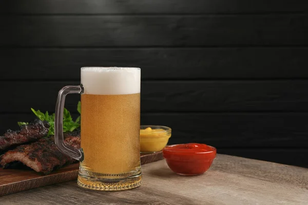 Taza Con Cerveza Deliciosas Costillas Parrilla Salsas Sobre Mesa Madera — Foto de Stock