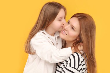 Turuncu arka planda mutlu anne ve tatlı kızının portresi.