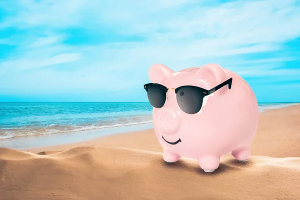 stock image Vacation savings. Piggy bank with sunglasses on sandy beach near sea. Space for text