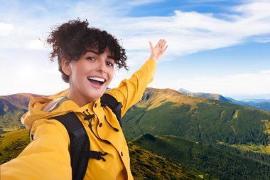 Güzel genç bir kadın dağlarda selfie çekiyor.