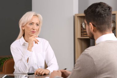 Ofisteki ahşap masada iş meselelerini tartışan patron ve çalışan.