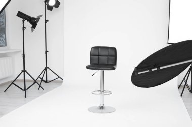 Interior of modern photo studio with bar stool and professional lighting equipment