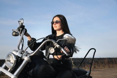 Beautiful young woman riding motorcycle on sunny day