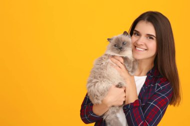 Turuncu arka planda sevimli kedisi olan mutlu kadın, mesaj için yer var.