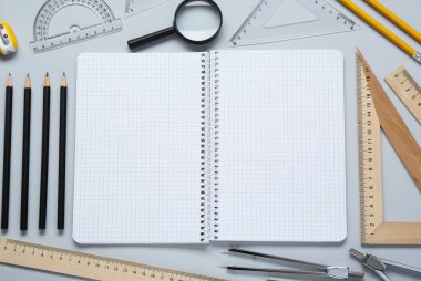 Açık gri arkaplan üzerinde çizim için farklı cetvel, defter ve diğer kırtasiye araçları, düz yatıyordu