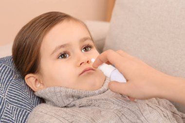 Anne, küçük kızını tedavi etmek için burun spreyi kullanıyor.