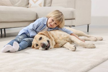 Evinde yerde Golden Retriever 'ı olan sevimli küçük bir çocuk. Sevimli hayvan.