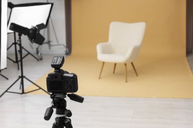 Kamera tripoda, koltuk ve profesyonel ışıklandırma ekipmanları modern fotoğraf stüdyosunda, metin için yer