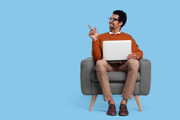 Homem Feliz Com Laptop Sentado Poltrona Apontando Para Algo Fundo — Fotografia de Stock