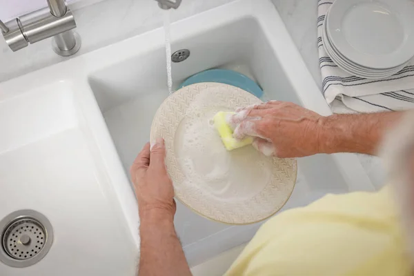 stock image Man washing plate above sink, top view