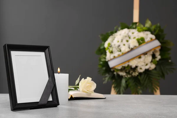 黒いリボン ライトテーブルの上に燃えるろうそくとグレーの壁の近くの花の花輪を屋内で テキストのためのスペースを持つ写真フレーム 葬儀の属性 — ストック写真