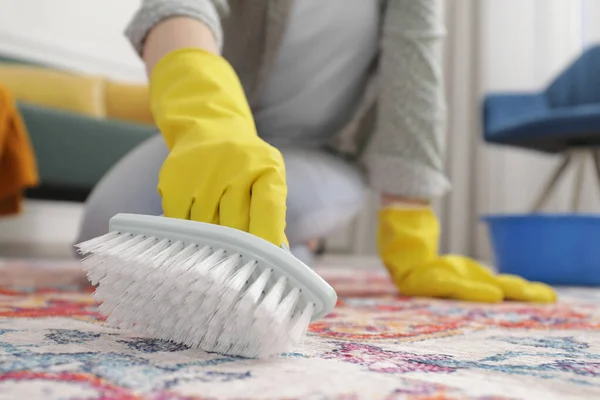Woman cleaning carpet with brush indoors, closeup. Space for text