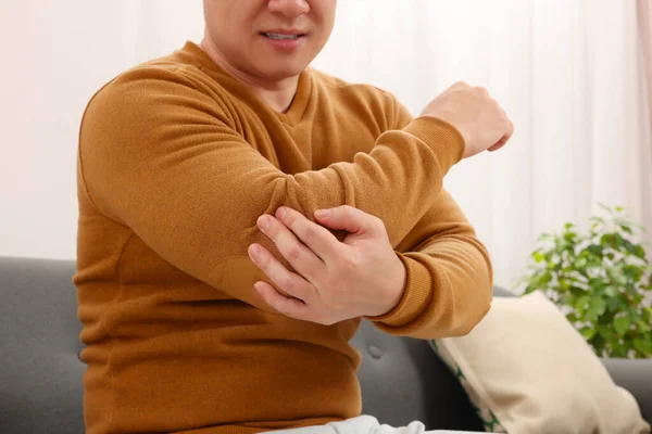 Man Suffering Pain His Elbow Sofa Indoors Closeup — Stock Photo, Image