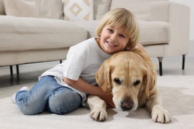 Evinde yerde Golden Retriever 'ı olan sevimli küçük bir çocuk. Sevimli hayvan.