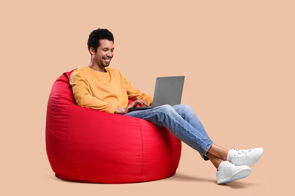 Homem Feliz Com Laptop Sentado Cadeira Beanbag Contra Fundo Bege — Fotografia de Stock