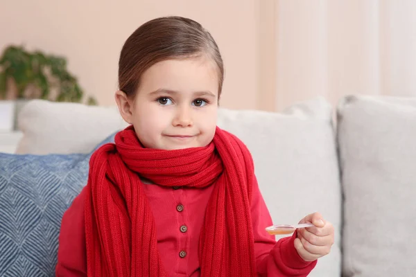 ソファに咳止めシロップをかけたスプーンを屋内で持っている可愛い女の子 効果的な薬 — ストック写真