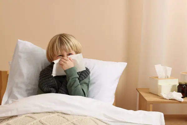 男孩在家里的床上用鼻涕在组织里吹气 感冒症状 — 图库照片