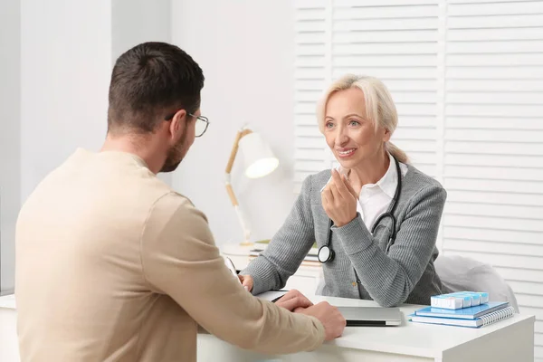 stock image Doctor consulting patient at white table in clinic