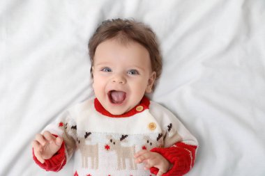 Yumuşak yatağın üstünde Noel süveteri içinde şirin bir bebek, üst manzara. Metin için boşluk