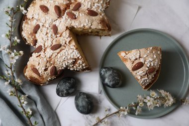 Lezzetli İtalyan Paskalya güvercini pastası (geleneksel Colomba di Pasqua), beyaz mermer masa üzerinde güzel çiçekler ile boyanmış yumurta ve dallar, düz yatıyordu