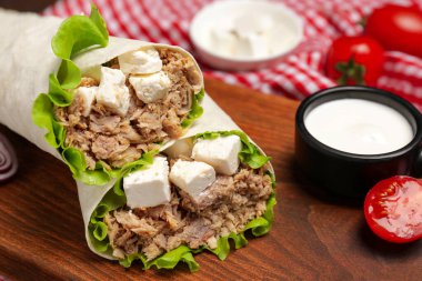 Lezzetli tortilla ahşap tahtada ton balığıyla sarılmış, yakın plan.