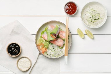 Beyaz ahşap masada servis edilen pirinç kağıdına sarılı nefis börekler.