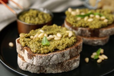 Pesto soslu lezzetli bruschettalar ve tabakta fındıklar, yakın plan.