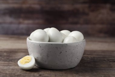 Pek çok soyulmuş bıldırcın yumurtası ahşap masada, yakın planda.