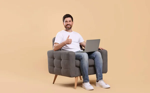 Homem Feliz Com Laptop Sentado Poltrona Mostrando Polegar Contra Fundo — Fotografia de Stock