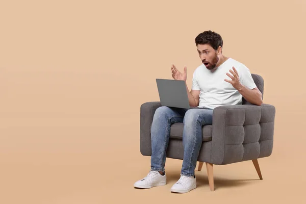 Homem Emocional Com Laptop Sentado Poltrona Contra Fundo Bege Espaço — Fotografia de Stock