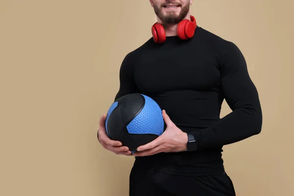 茶色の背景にヘッドフォンや医療ボールを持つスポーツマン クローズアップ テキストのスペース — ストック写真