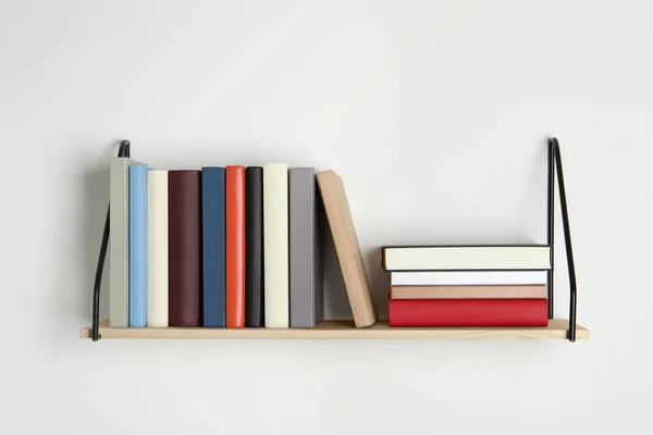 白色墙壁上有许多精装书的木制书架 — 图库照片