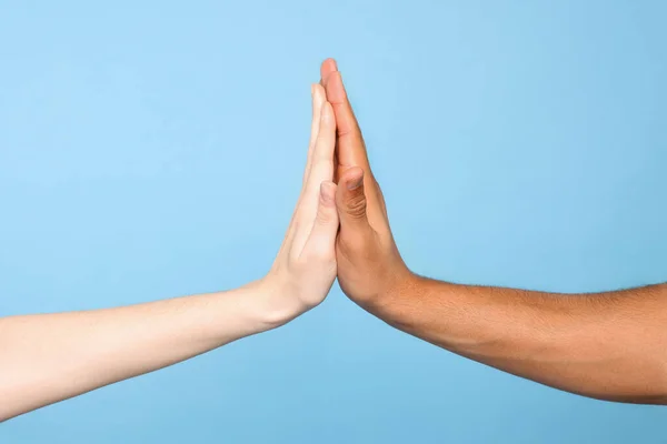International relationships. People giving high five on light blue background, closeup