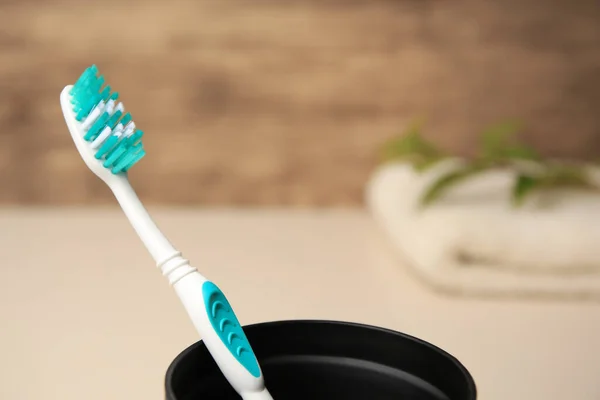 Toothbrush in holder on blurred background, closeup. Space for text