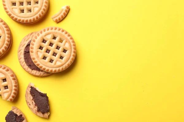 Tasty sandwich cookies with cream on yellow background, flat lay. Space for text