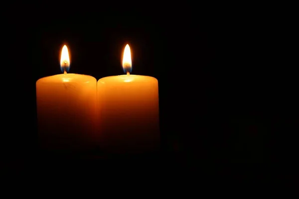 Burning wax candles on black background, closeup. Space for text