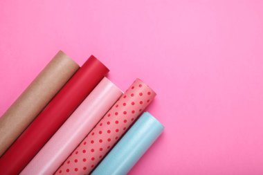 Pembe arka planda renkli ambalaj kağıtları, düz yatış. Metin için boşluk