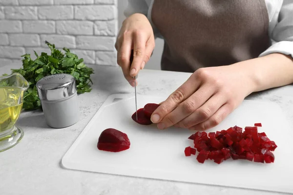 Beyaz masada pancar kesen kadın, yakın plan. Sirkeli salata pişiriyorum.