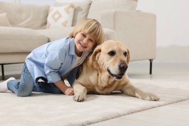 Evinde yerde Golden Retriever 'ı olan sevimli küçük bir çocuk. Sevimli hayvan.
