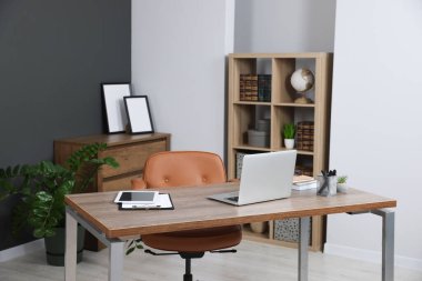 Modern mobilyaları ve ahşap masasında dizüstü bilgisayarı olan şık bir ofis. İç tasarım
