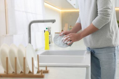 Adam lavabonun üstündeki tabağı yıkıyor, yakın plan.