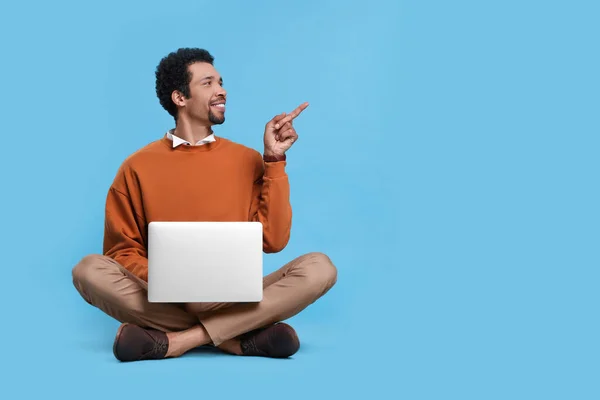 Homem Bonito Com Laptop Apontando Para Algo Fundo Azul Claro — Fotografia de Stock