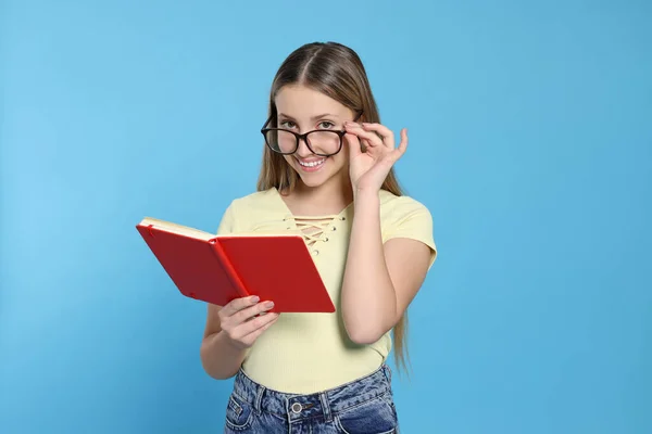 Teenager Mädchen Mit Brille Liest Buch Auf Hellblauem Hintergrund — Stockfoto